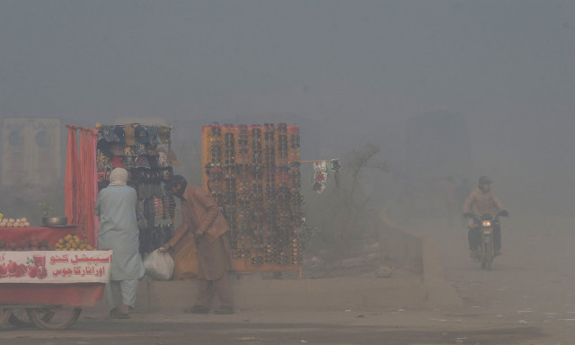 a vendor arranges his stall beside a street amid heavy smoggy conditions in lahore on november 18 photo afp a vendor arranges his stall beside a street amid heavy smoggy conditions in lahore on november 18 photo afp