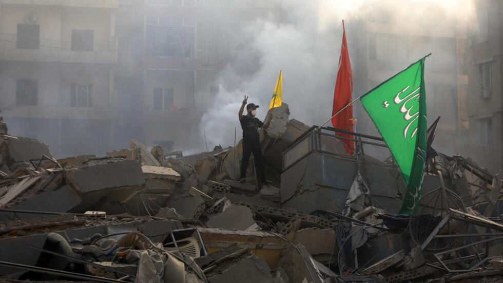 a man poses with hezbollah banners on the rubble of a building flattened in an israeli air strike that targeted beirut s southern suburbs photo afp