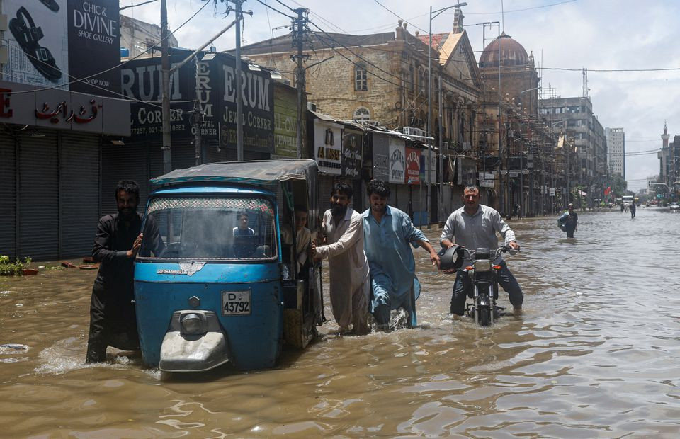 Residents commute through a flooded street during the monsoon season, in Karachi, Pakistan July 11, 2022. REUTERS