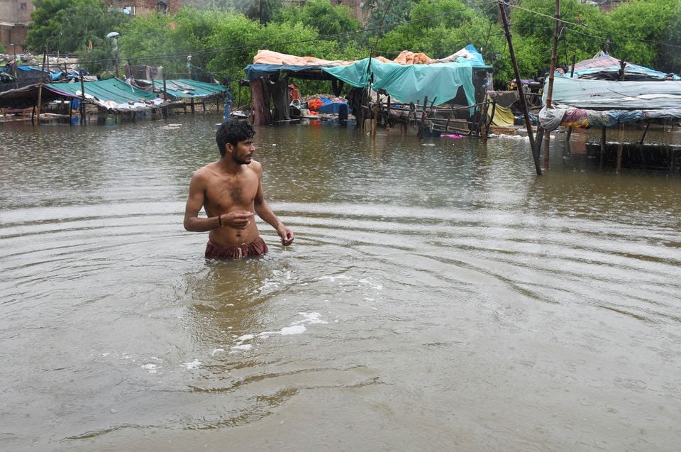 A man walks amid floodwaters with the submerged tents in the background, following rains during the monsoon season in Hyderabad, Pakistan August 24, 2022. REUTERS