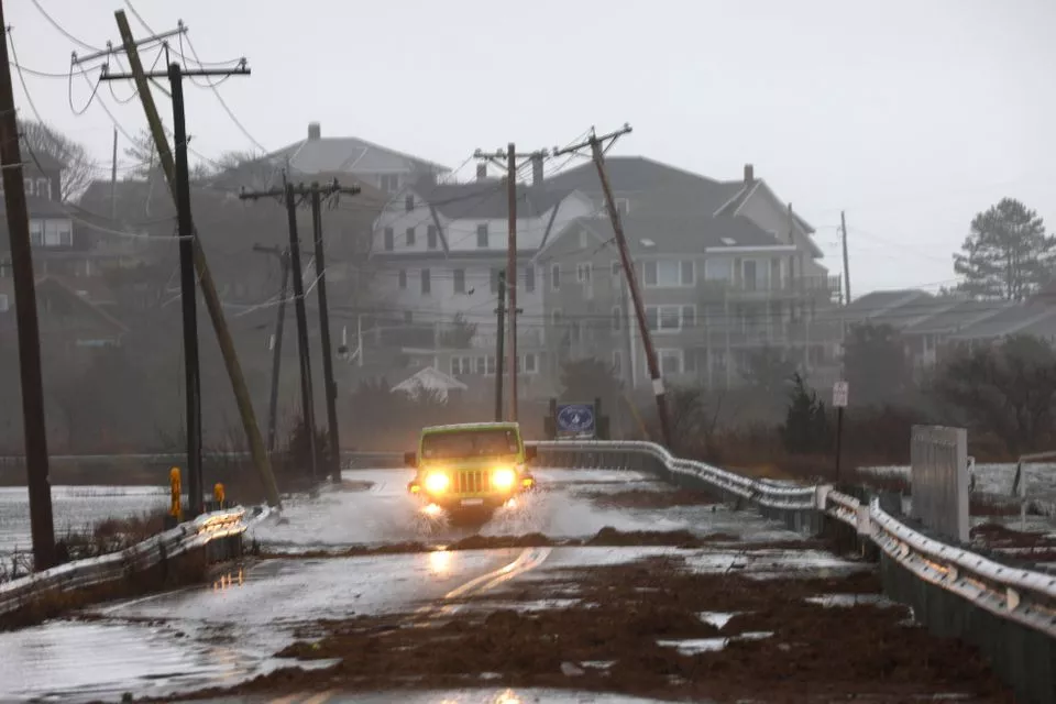 a driver makes their way through a flooded street at high tide during a winter storm in gloucester massachusetts u s december 23 2022 reuters brian snyder