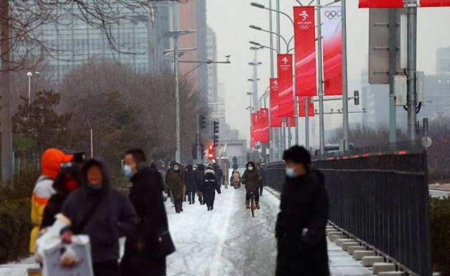 people walk during snowfall outside the closed loop area designed to prevent the spread of the coronavirus disease covid 19 near the main press centre ahead of the beijing 2022 winter olympics in beijing china january 20 2022 reuters people walk during snowfall outside the closed loop area designed to prevent the spread of the coronavirus disease covid 19 near the main press centre ahead of the beijing 2022 winter olympics in beijing china january 20 2022 reuters