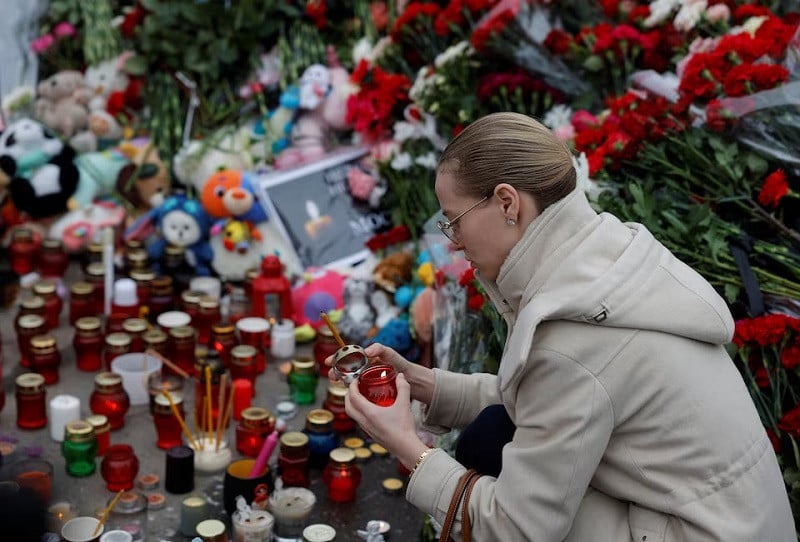 A woman lights a candle at a memorial to the victims of a shooting attack at the Crocus City Hall concert venue near Moscow, March 24, 2024. PHOTO: REUTERS