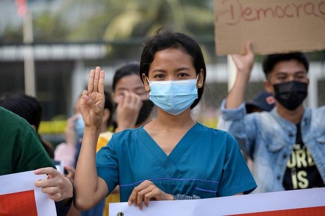 a nurse show the three finger salute as she takes part in a protest against the military coup and to demand the release of elected leader aung san suu kyi in yangon myanmar february 8 2021 photo reuters