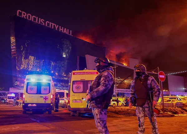 Law enforcement officers stand guard near the burning Crocus City Hall concert venue following the terror attack, outside Moscow, Russia. PHOTO: Reuters