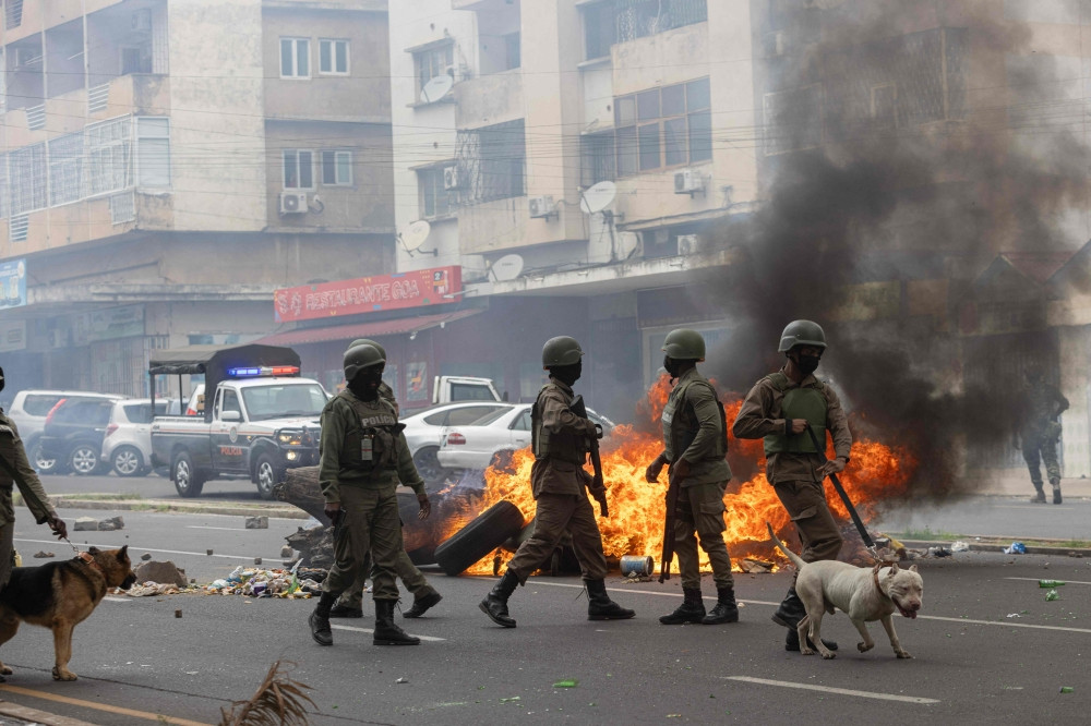 anti riot police officers with their dogs walk down eduardo mondlane avenue past burning barricades made by protesters in maputo on november 7 2024 photo afp