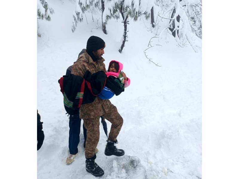 a soldier shifting children to an army relief camp established in murree division photo ispr