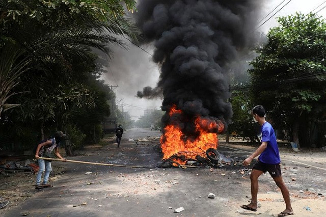 an anti coup protester walks past burning tires after activists launched a garbage strike against the military rule in yangon myanmar march 30 2021 photo reuters