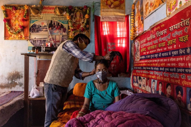 suresh kumar 43 ties up the hair of his wife pramila devi 36 who is suffering from the coronavirus disease covid 19 before taking her to a local government dispensary at their home in kaljikhal in the northern state of uttarakhand india may 23 2021 devi s eldest daughter got married and moved away in late april after the family hosted a ceremony attended by over two dozen people her husband suresh kumar 43 told reuters two weeks after that devi suffered a bout of diarrhoea but it was not until 10 days later that kumar who has no income and depends on handouts took her to a nearby dispensary that has been turned into a small covid 19 facility with four beds devi tested positive for covid 19 with very low blood oxygen levels she died a day later reuters