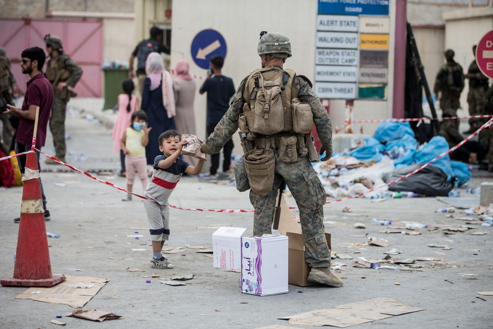 A U.S. Marine provides a meal ready-to-eat to a child during an evacuation at Hamid Karzai International Airport, Kabul, Afghanistan, August 21, 2021. Picture taken August 21, 2021. U.S. Marine Corps/Sgt. Samuel Ruiz/Handout via REUTERS