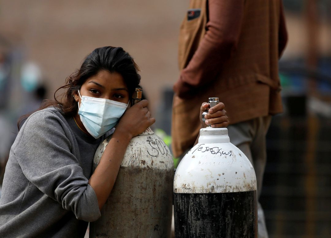 a woman holds on to the oxygen cylinders for a patient after refiling them at a factory amidst the spread of coronavirus disease covid 19 surge as india s outbreak spreads across south asia in kathmandu nepal may 9 2021 photo reuters