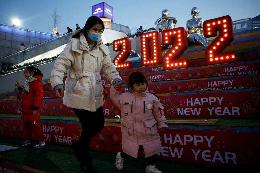 A woman wearing a face mask, following the coronavirus disease (COVID-19) outbreak, walks with a child past a 2022 installation on New Year's Eve at a shopping mall in Beijing, China December 31, 2021. PHOTO: REUTERS