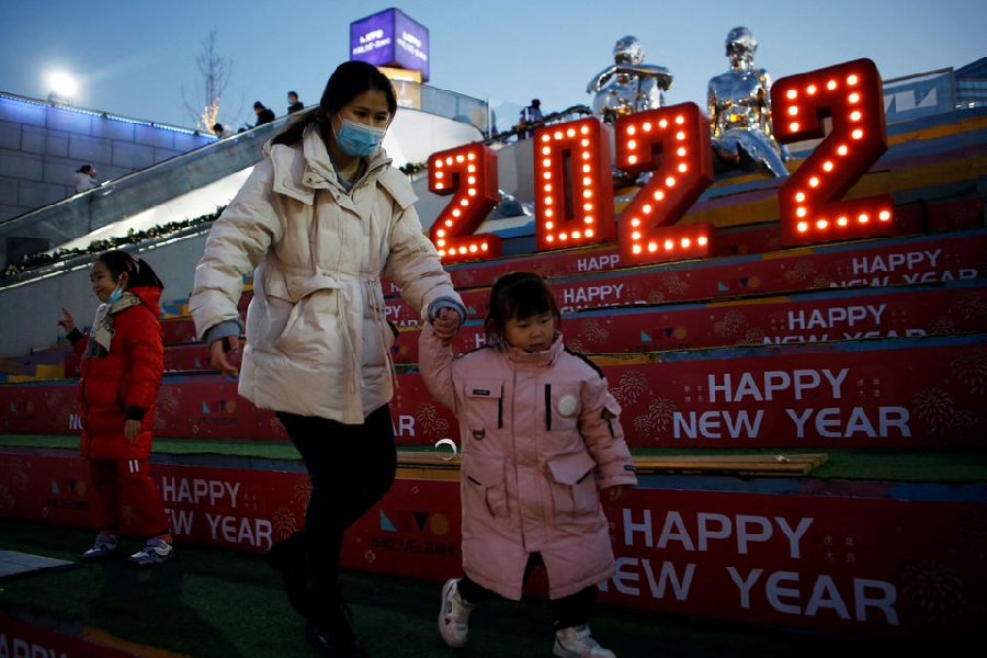 a woman wearing a face mask following the coronavirus disease covid 19 outbreak walks with a child past a 2022 installation on new year s eve at a shopping mall in beijing china december 31 2021 photo reuters