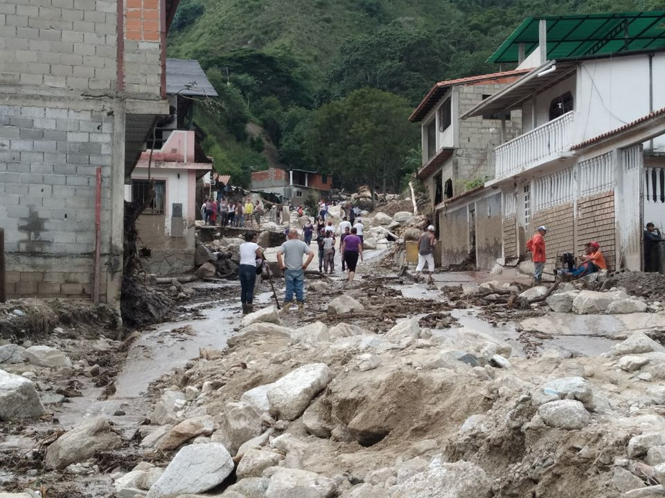 people walk on the street covered in mud following flash flooding in tovar merida state venezuela august 25 2021 photo reuters