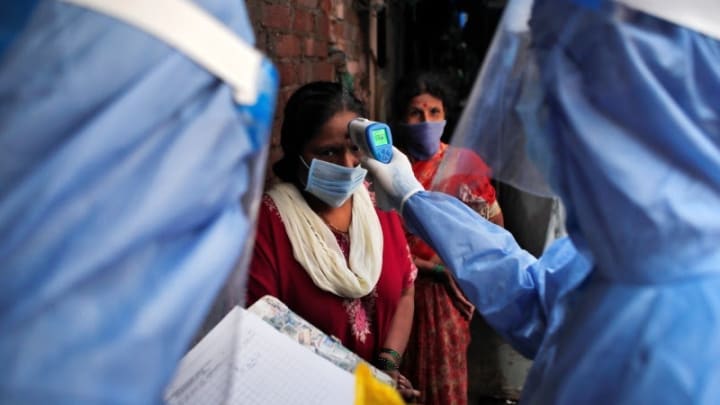 a health care worker checks a woman s temperature during a covid 19 campaign at a slum area in mumbai india photo reuters