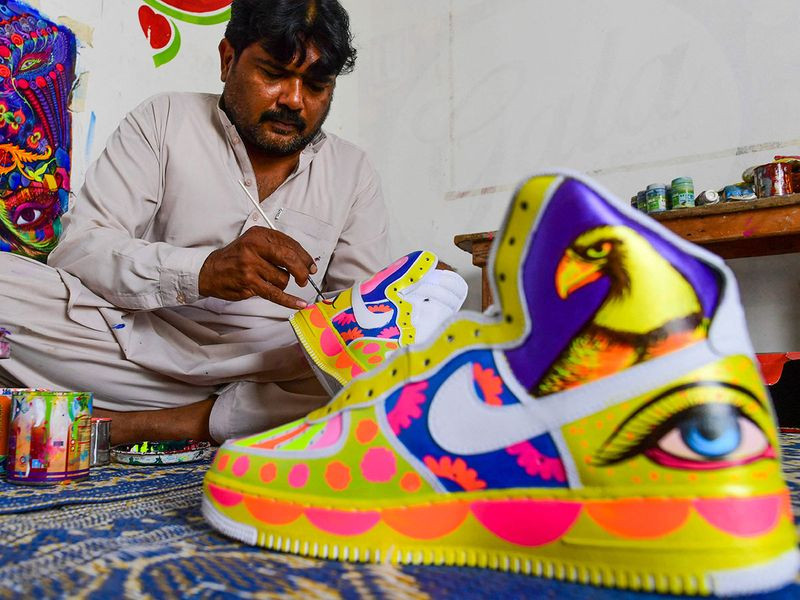 haider ali dabs a brush with an iridescent glob of paint and gets to work on a pair of sparkling white trainers   his latest canvas for a carnival of colour celebrating pakistani culture photo afp