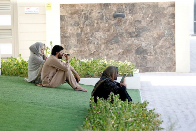 afghani evacuees sit in a park and talk to their families back home at a temporary residence compound in doha qatar august 27 2021 photo reuters