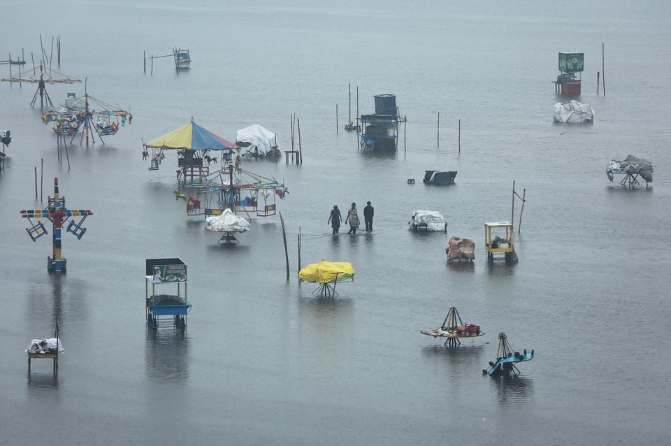 people wade through a flooded beach after heavy rainfall in chennai india november 8 2021 reuters