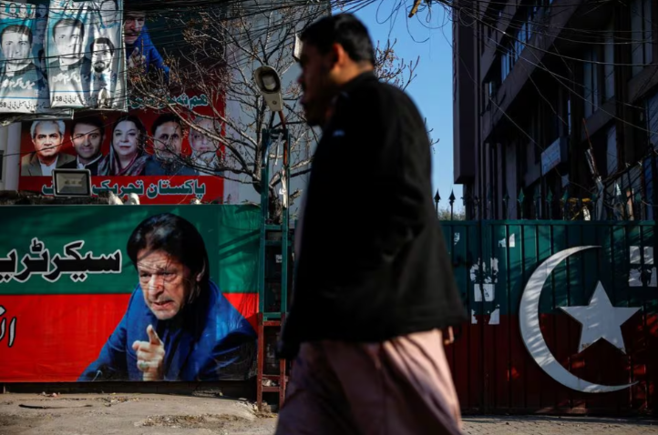 people walk past a banner with a picture of the former prime minister imran khan outside the party office of pakistan tehreek e insaf pti a day after the general election in lahore pakistan february 9 2024 reuters navesh chitrakar