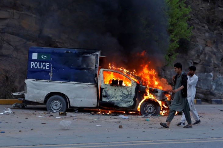 men walk past a burning police vehicle during clashes between the supporters of former pakistani prime minister imran khan and police in islamabad pakistan march 18 2023 reuters fayaz aziz