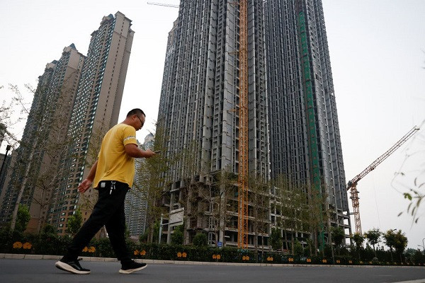 a man walks in front of unfinished residential buildings at the evergrande oasis a housing complex developed by evergrande group in luoyang china september 15 2021 photo reuters