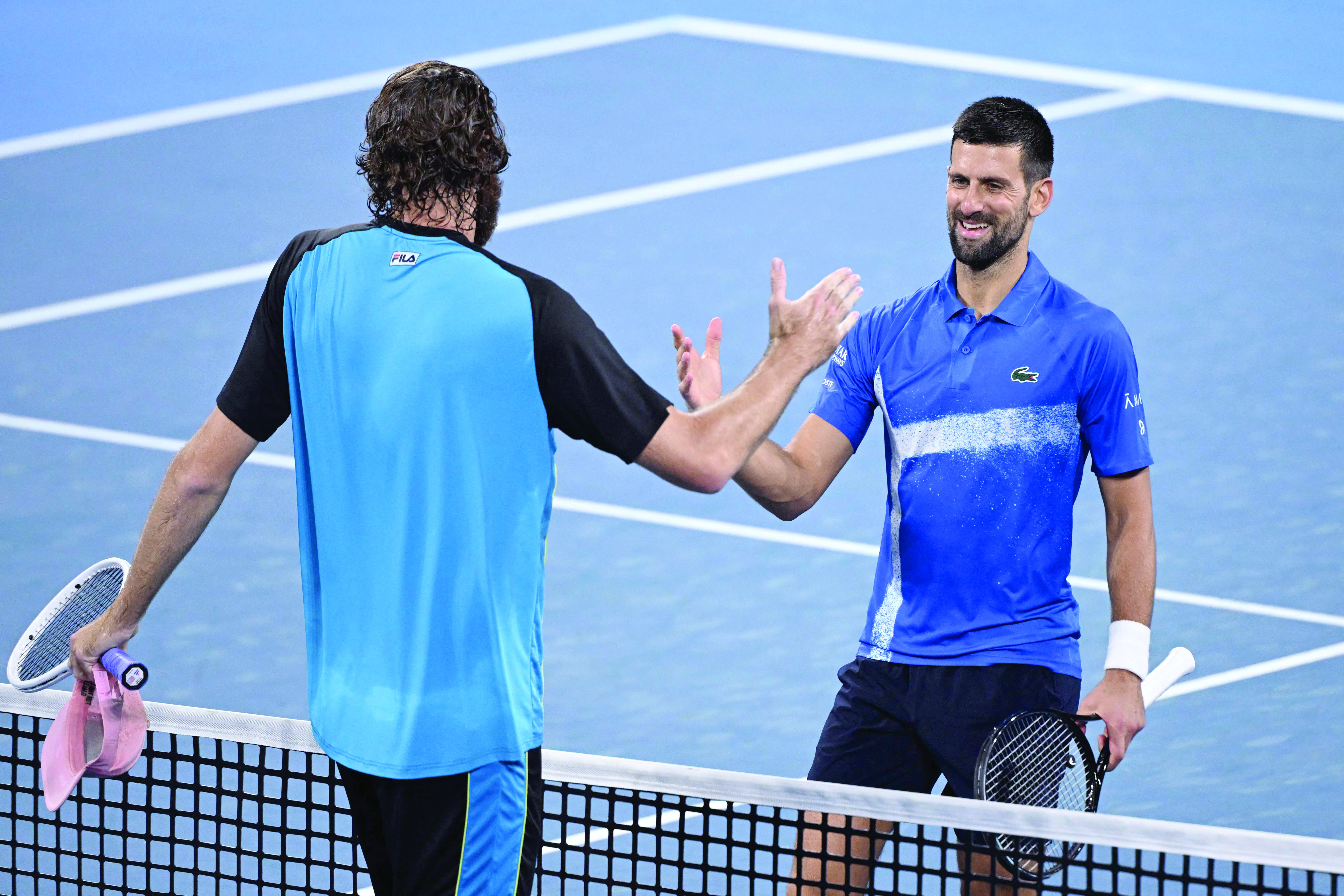 winner reilly opelka l and novak djokovic shake hands at the net after their men s singles quarter final of the brisbane international tennis tournament photo afp