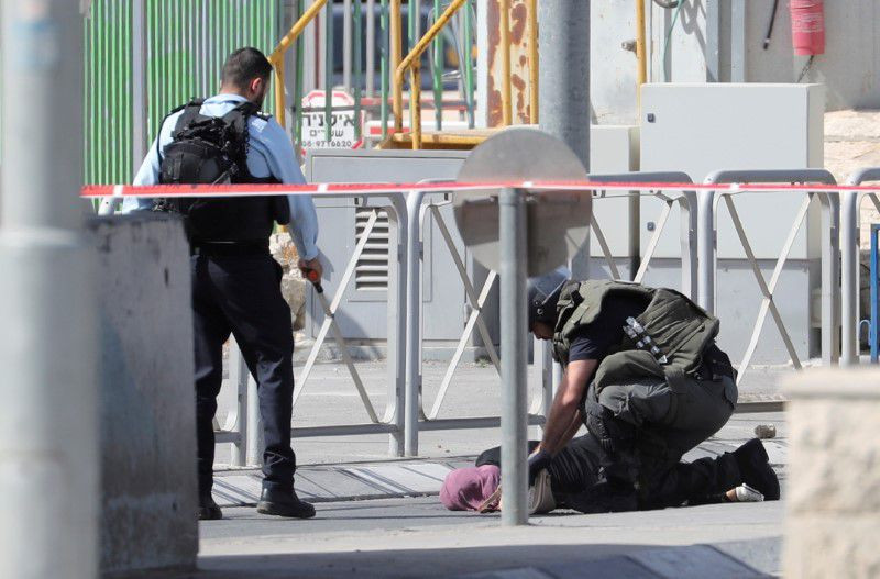 members of the israeli forces approach a woman lying on the ground at the site of a security incident near ramallah in the israeli occupied west bank june 12 2021 photo reuters