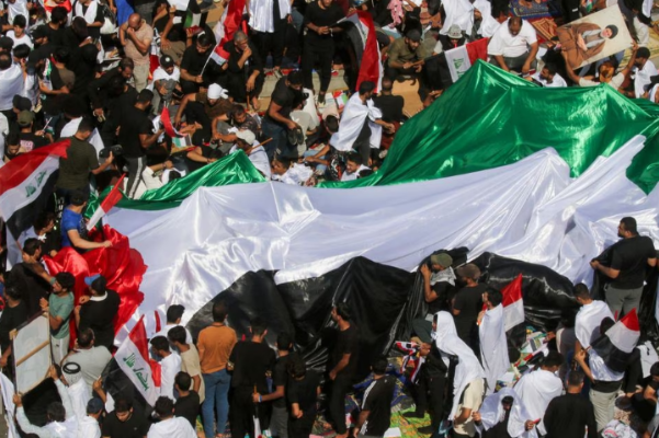 People hold a flag as supporters of Iraqi cleric Moqtada al-Sadr gather during a protest in solidarity with Palestinians in Gaza, in Baghdad, Iraq. PHOTO: Reuters