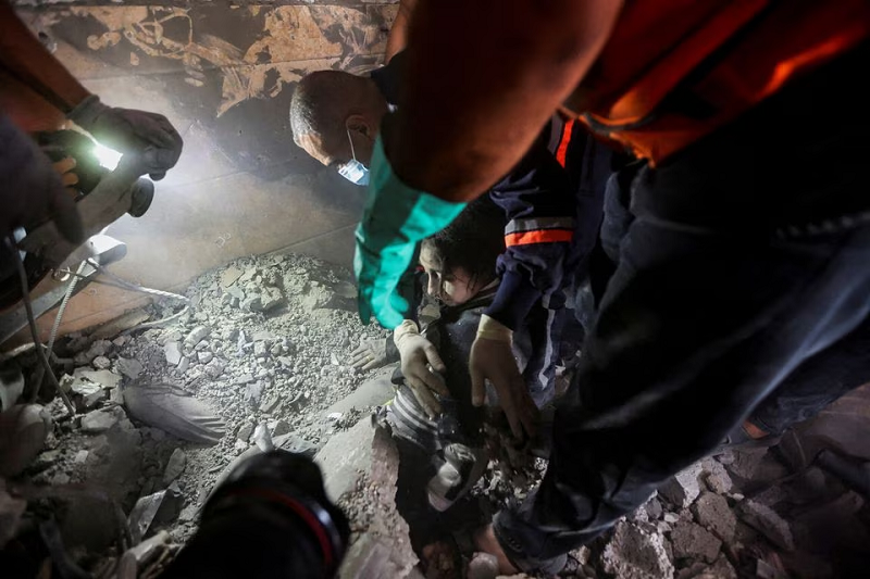 Emergency personnel work to rescue a Palestinian woman at the site of Israeli raids on a residential building in Khan Younis in the southern Gaza Strip November 7, 2023. PHOTO: REUTERS