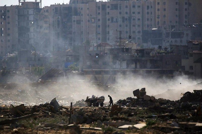 a palestinian man salvages items from a waste dump atop rubble at al bureij camp in the central gaza strip photo afp