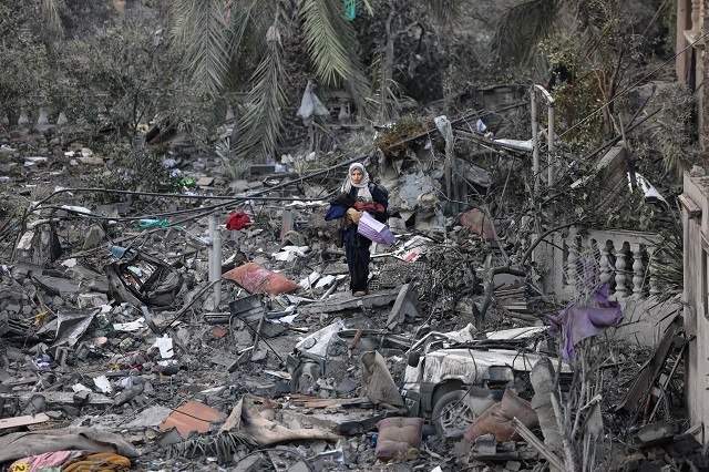 A Palestinian woman walks on building rubble following an Israeli strike in Rafah in the southern Gaza Strip. PHOTO: AFP