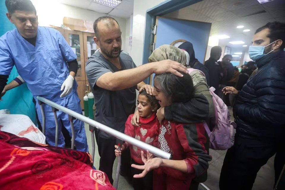 People react next to the bed of a Palestinian wounded in an Israeli strike, at a hospital in Khan Younis in the southern Gaza Strip, December 28, 2023. PHOTO: REUTERS