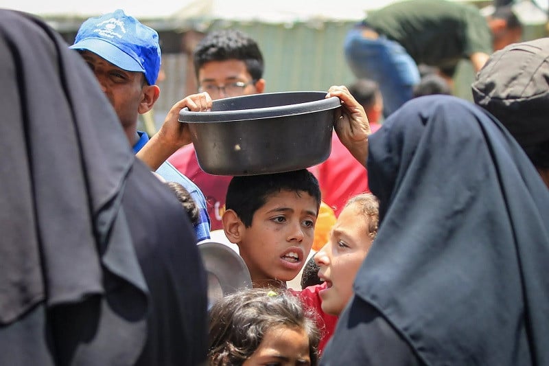 palestinians queue for meal rations at a communal food distribution point in al bureij refugee camp in the besieged gaza strip on june 3 2024 photo afp