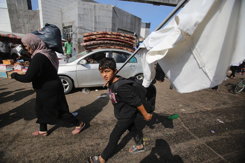 A Palestinian boy carries a makeshift white flag as he arrives with his mother near Al-Shifa hospital in Gaza City on November 6, 2023. PHOTO: AFP
