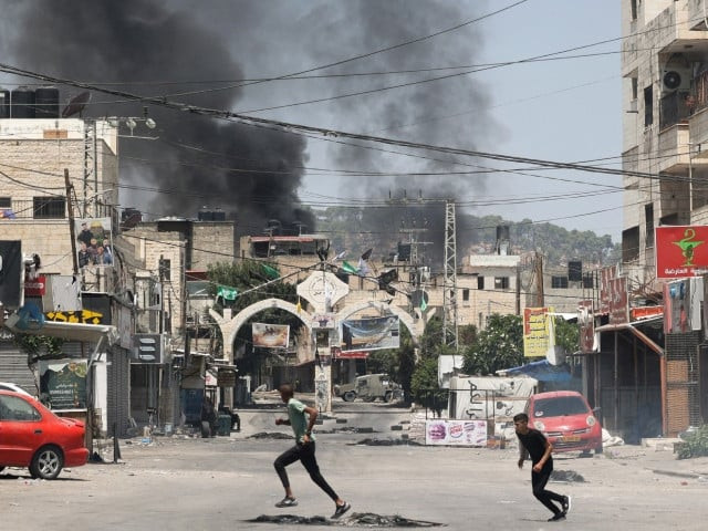 palestinian youths run for cover during an israeli military operation in jenin city in the occupied west bank photo afp