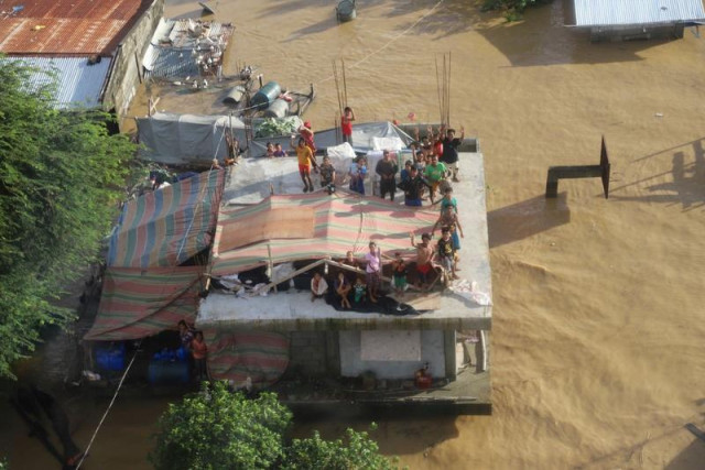 people stand on a roof of a building after typhoon vamco resulted in severe flooding in the cagayan valley region in the philippines november 14 2020 photo file people stand on a roof of a building after typhoon vamco resulted in severe flooding in the cagayan valley region in the philippines november 14 2020 photo file