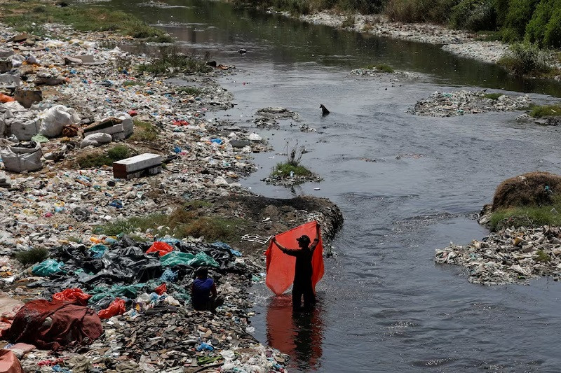 a man washes waste plastic sheets collected for recycling in the polluted waters on world environment day in karachi pakistan june 5 2023 photo reuters