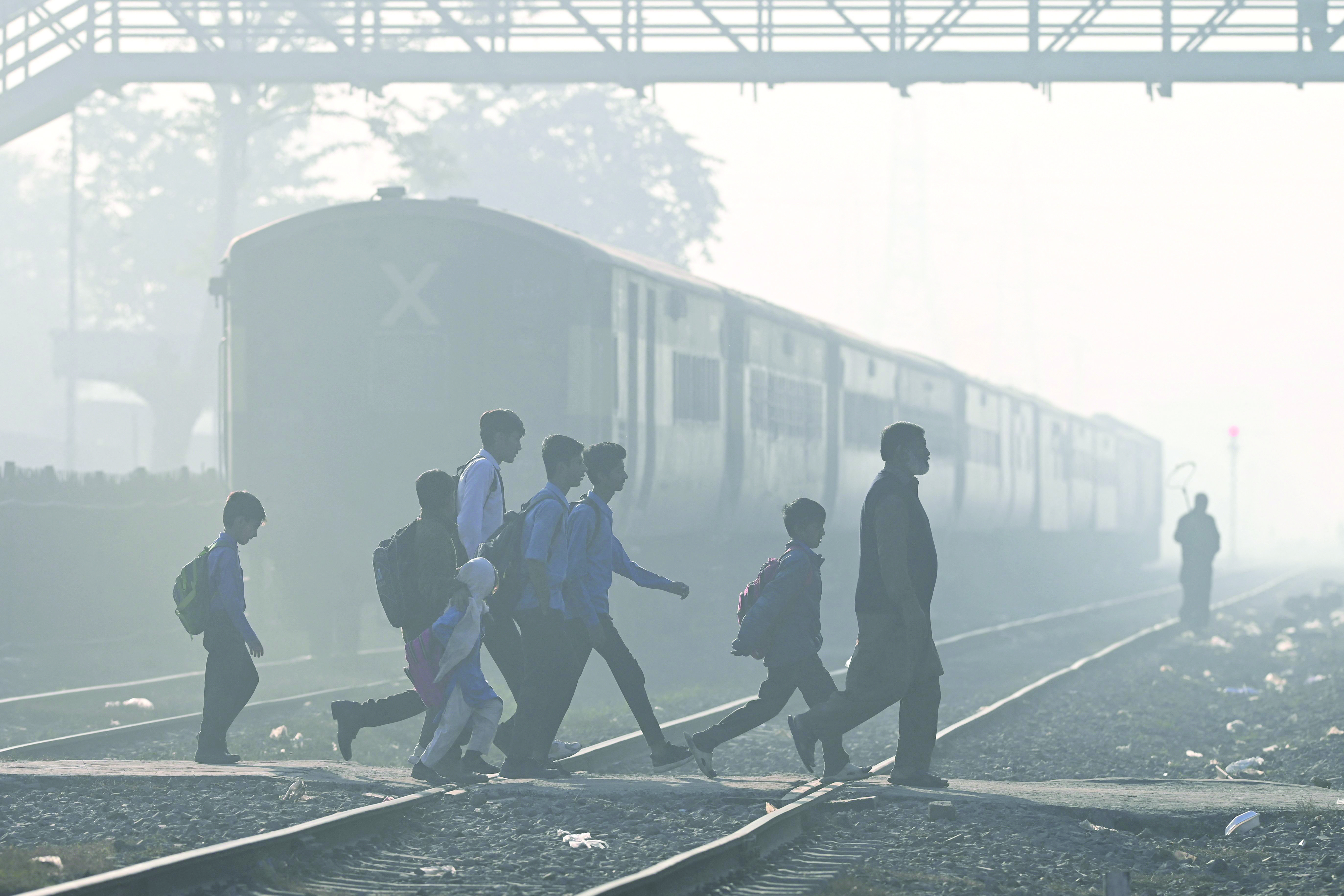 school children walk across a railway track engulfed in dense smog in lahore photo afp