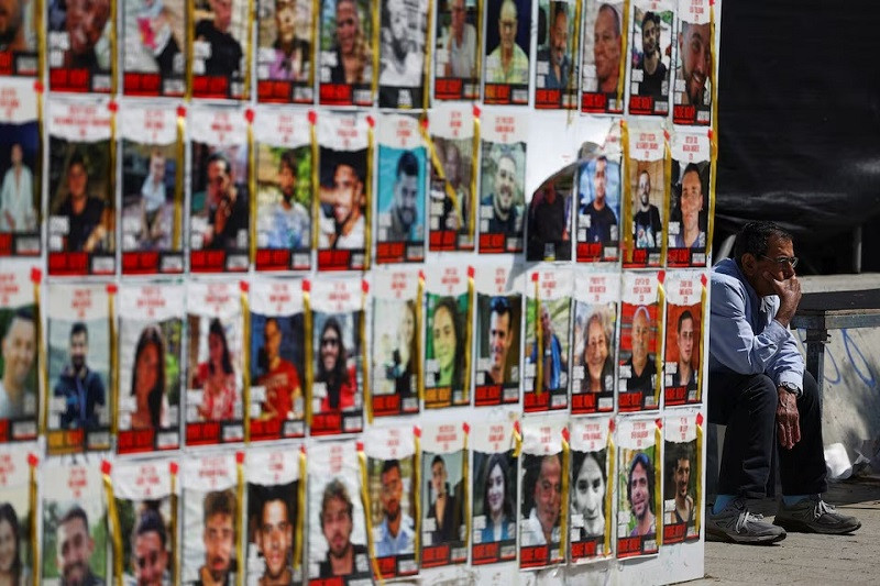 a man sits next to posters with images of hostages kidnapped in the deadly october 7 attack in tel aviv israel april 16 2024 photo reuters