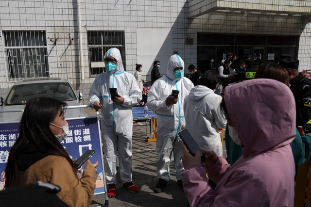 workers in protective suits check registration codes as people enter a nucleic acid testing site following the coronavirus disease covid 19 outbreak in beijing china april 6 2022 reuters workers in protective suits check registration codes as people enter a nucleic acid testing site following the coronavirus disease covid 19 outbreak in beijing china april 6 2022 reuters