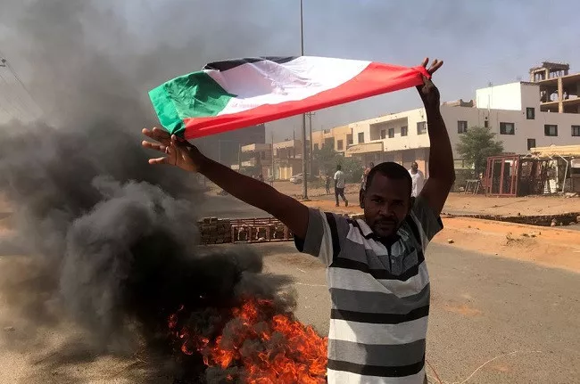 a protester waves a flag during what the information ministry calls a military coup in khartoum sudan october 25 2021 photo reuters a protester waves a flag during what the information ministry calls a military coup in khartoum sudan october 25 2021 photo reuters