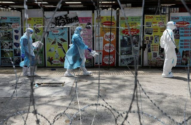 medical workers wearing protective suits pass by barbed wire in a red zone under enhanced lockdown amid the novel coronavirus outbreak in petaling jaya malaysia may 11 2020 photo reuters