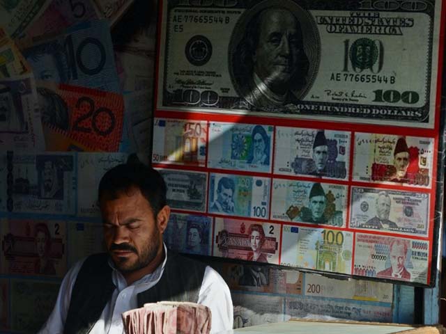 a pakistani currency dealer waits for customers at a currency exchange shop photo afp