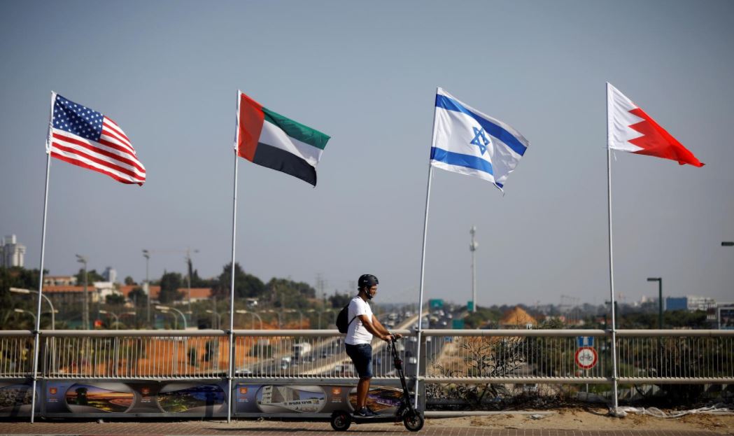 a man rides a scooter near the flags of the us united arab emirates israel and bahrain as they flutter along a road in netanya israel september 14 2020 photo reuters file
