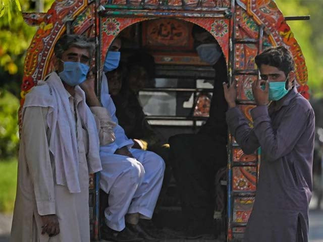 passengers wearing facemasks wait next to a vehicle in islamabad phot afp passengers wearing facemasks wait next to a vehicle in islamabad phot afp