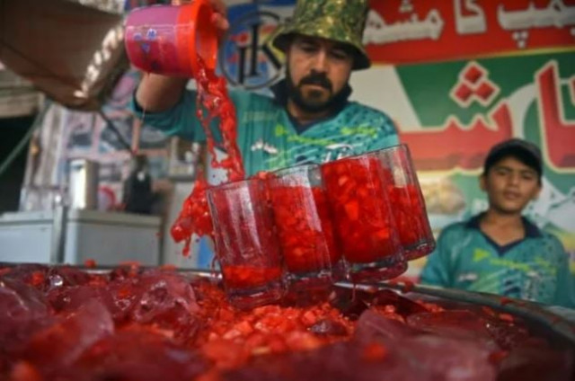 in this photograph taken on may 25 2022 a vendor prepares to serve rooh afza watermelon beverages to customers along a roadside stall in karachi photo afp in this photograph taken on may 25 2022 a vendor prepares to serve rooh afza watermelon beverages to customers along a roadside stall in karachi photo afp