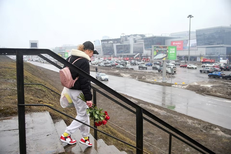 A woman carrying flowers walks near the Crocus City Hall concert venue following Friday's deadly attack, outside Moscow, Russia, March 23, 2024. PHOTO: REUTERS