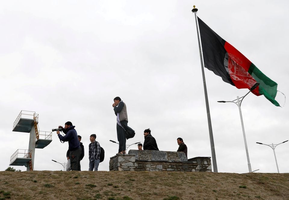 youths take pictures next to an afghan flag on a hilltop overlooking kabul afghanistan april 15 2021 photo reuters