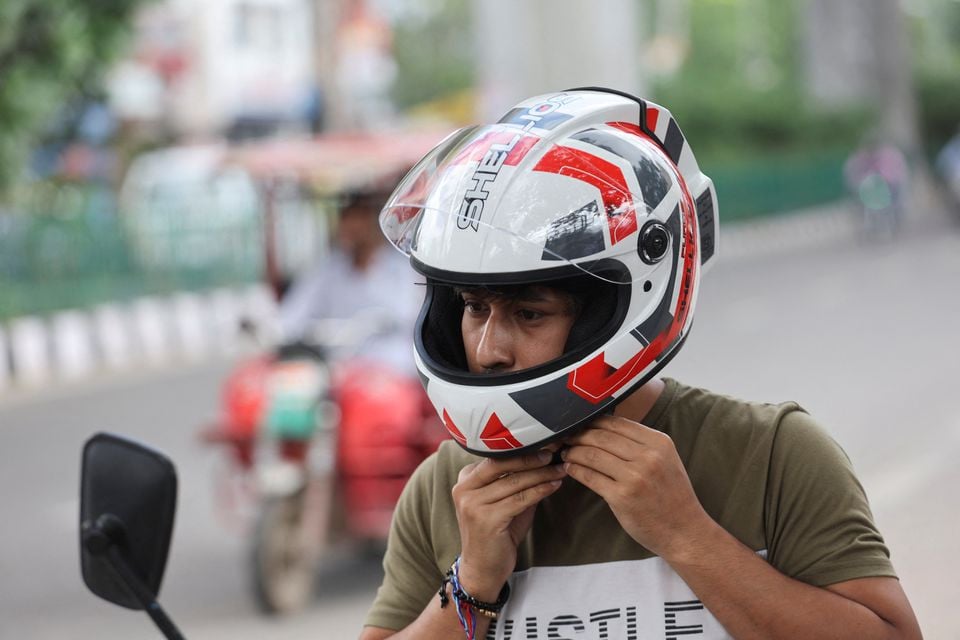 an employee of shellios technolabs that manufactures motorcycle helmet claimed to be fitted with filters and a fan at the back of the helmet puts on the helmet near their assembling factory unit in an industrial area in new delhi india august 23 2022 reuters