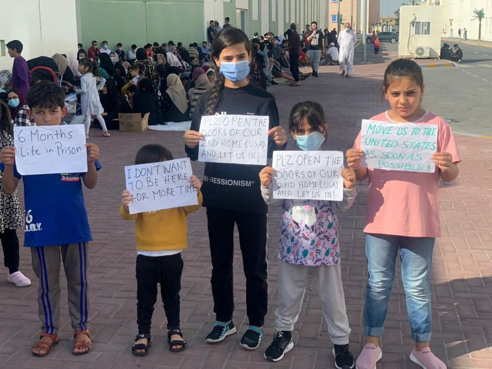 afghan children hold banners during a protest over lengthy us relocation process at a gulf facility where they have been housed since fleeing their homeland last year in abu dhabi united arab emirates february 10 2022 in this picture obtained from social media photo reuters